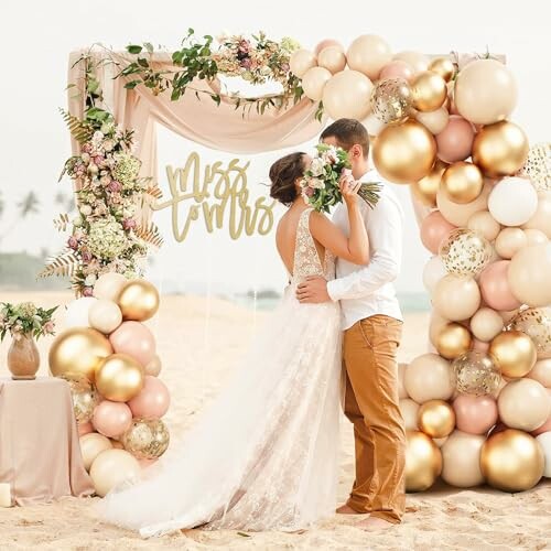 Bride and groom kissing under a balloon arch on the beach