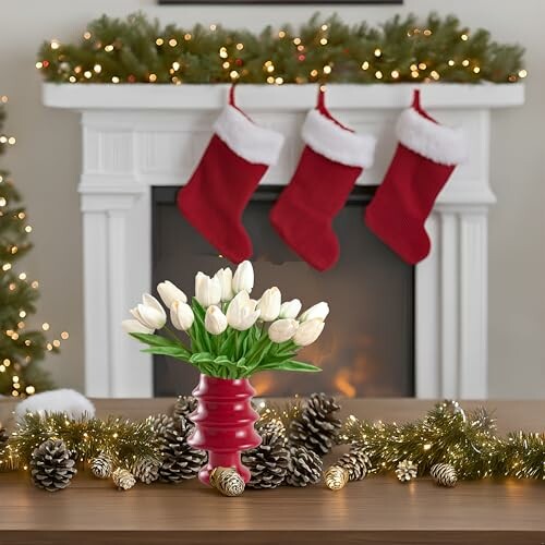 Festive mantel with stockings and tulips in a red vase, showcasing holiday decor.