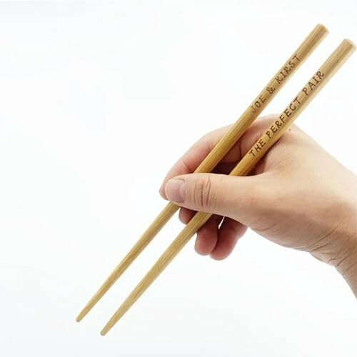 Hand holding custom engraved chopsticks.