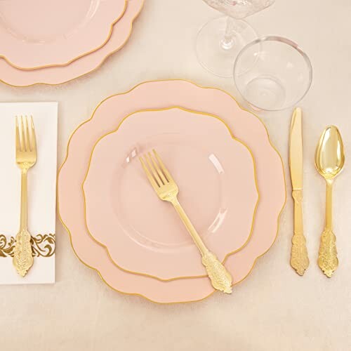 Elegant pink and gold table setting with plates and cutlery.