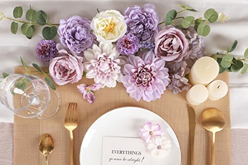 Elegant table setting with purple and white flowers, gold cutlery, and candles