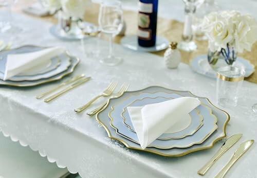 Elegant table setting with white and gold plates, napkins, and floral decorations.