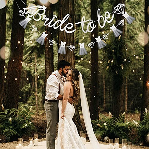 Bride and groom embracing under 'Bride to be' banner in forest setting