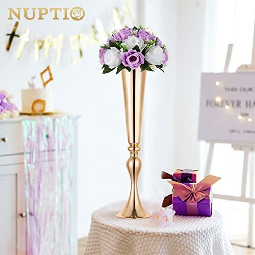 Elegant gold vase with purple and white flowers on a table