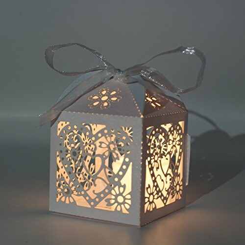 Decorative illuminated paper lantern with intricate cut-out design and ribbon.