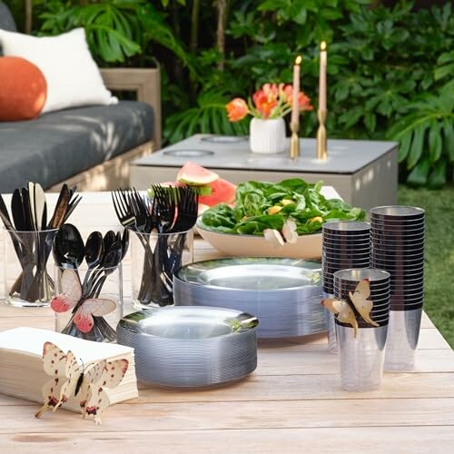 Outdoor table with plates, cutlery, cups, salad, and decorative butterflies.