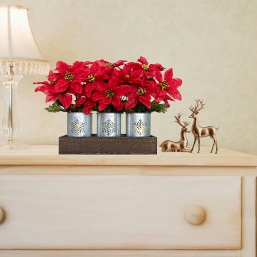 Table decor with red poinsettias and deer figurines.