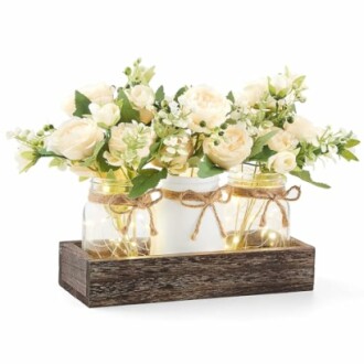 Rustic floral centerpiece with cream flowers in mason jars on a wooden tray.