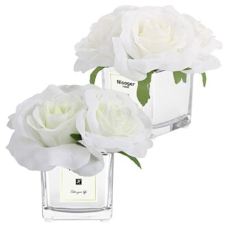 Two arrangements of artificial white roses in square glass vases.