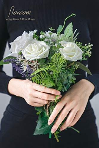 Person holding a bouquet of white roses and greenery